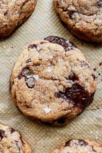 Brown butter sourdough chocolate chip cookies stacked with gooey chocolate and flaky sea salt on top.