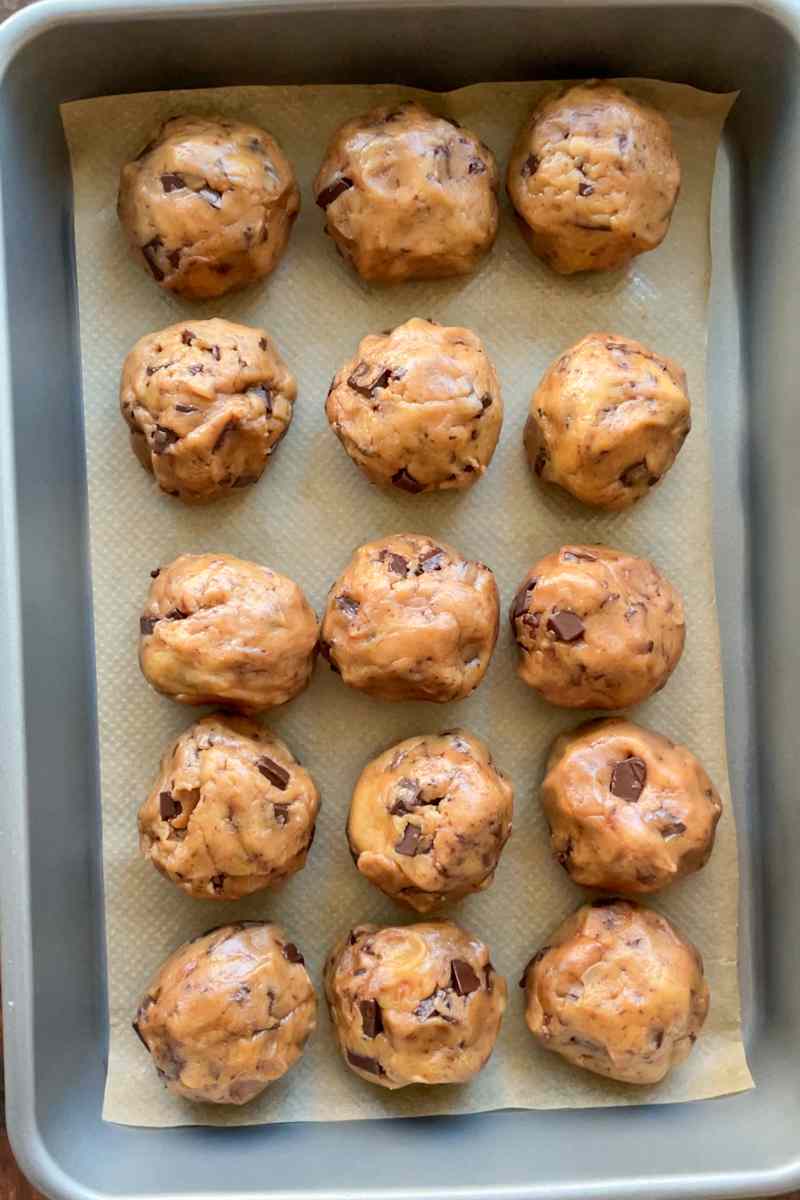 Shaped sourdough cookie dough balls ready to chill on a baking sheet.