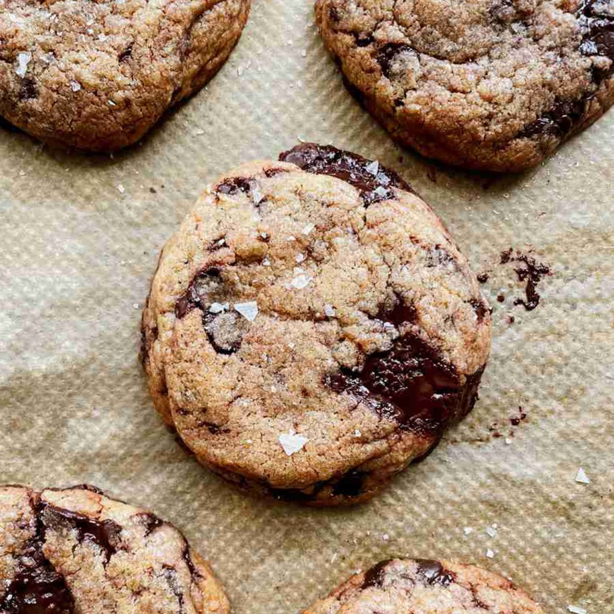 Brown butter sourdough chocolate chip cookies stacked with gooey chocolate and flaky sea salt on top.