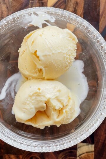 Scoops of homemade vanilla custard ice cream in a bowl showing a creamy texture