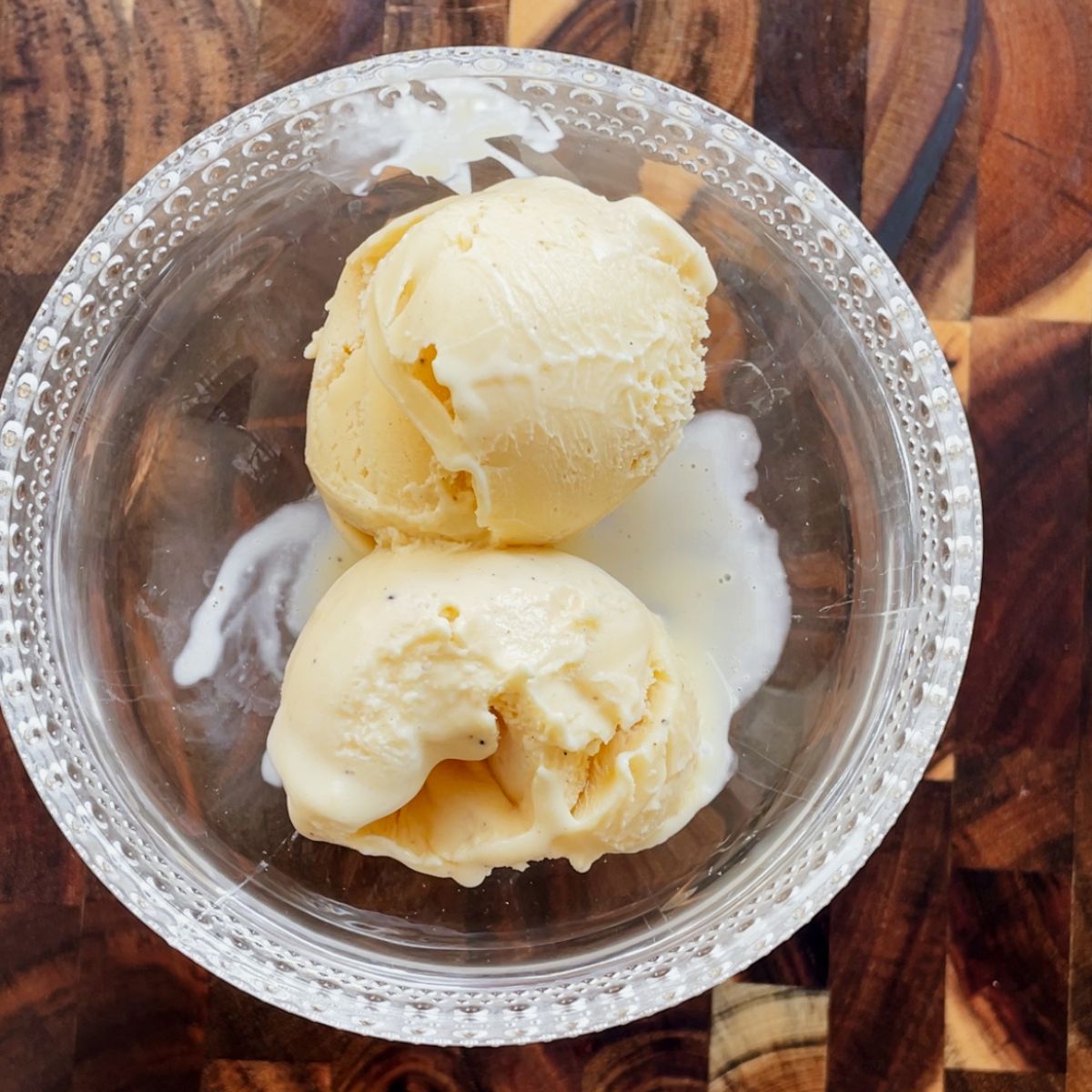 Scoops of homemade vanilla custard ice cream in a bowl showing a creamy texture