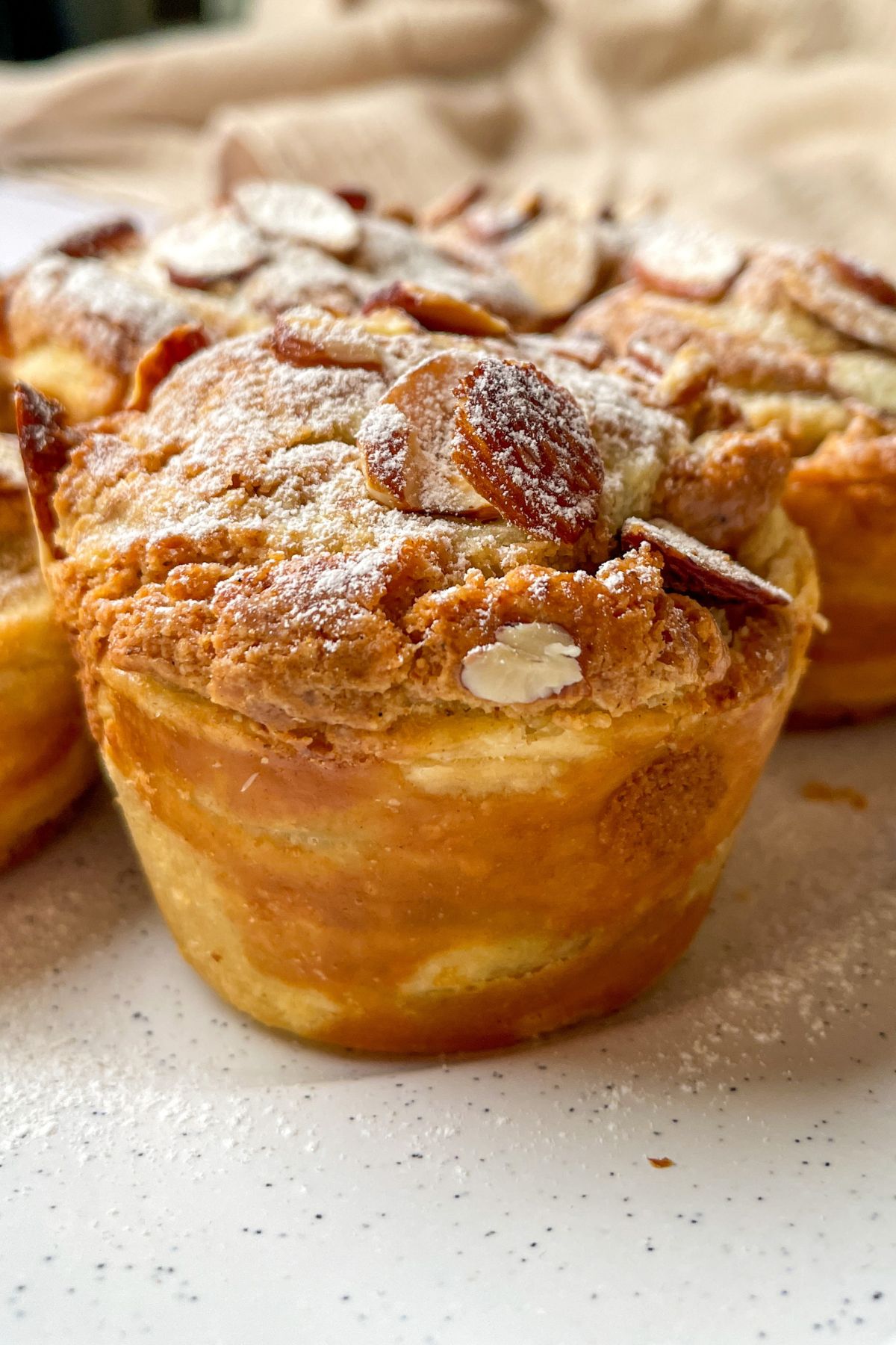 Close-up of a sourdough almond cruffin showing flaky puff pastry layers and almond frangipane inside