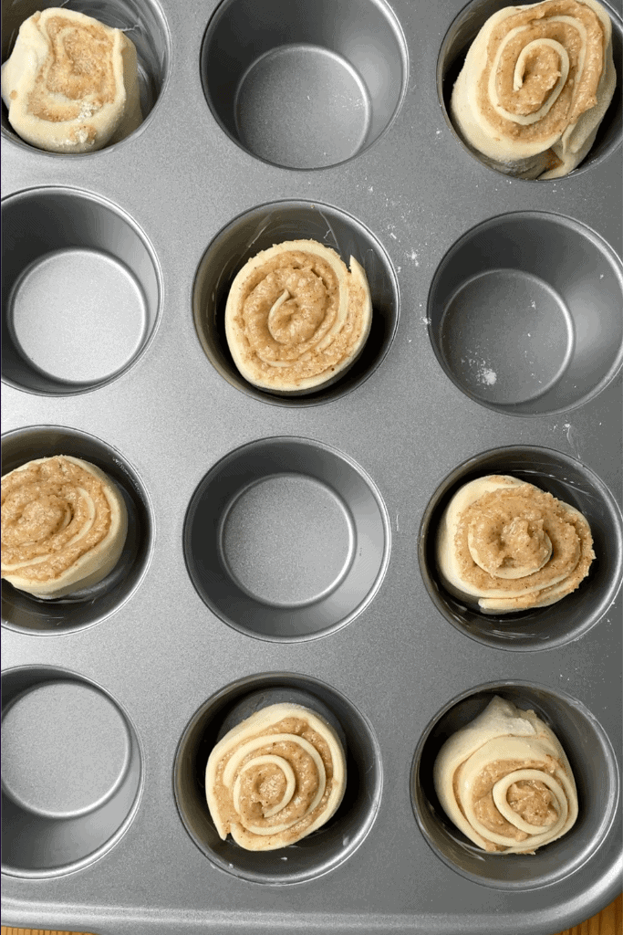 Unbaked sourdough cruffins placed in a greased muffin tin