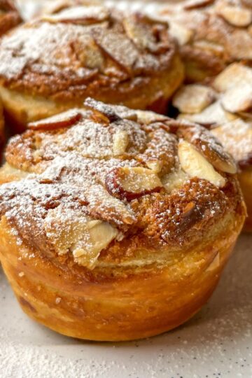 Freshly baked sourdough almond cruffins with flaky layers and sliced almonds on top