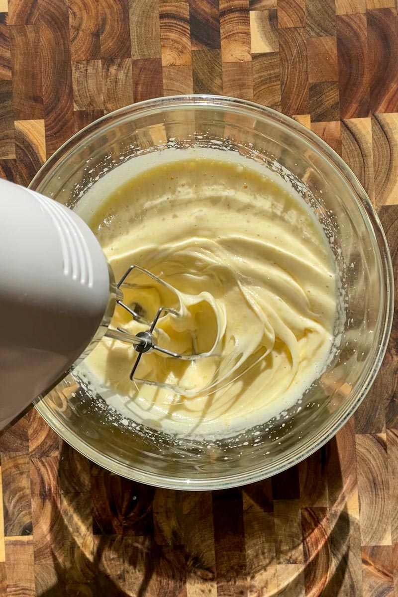 Whisking eggs and lemon sugar mixture until pale and doubled in volume for sourdough lemon loaf batter