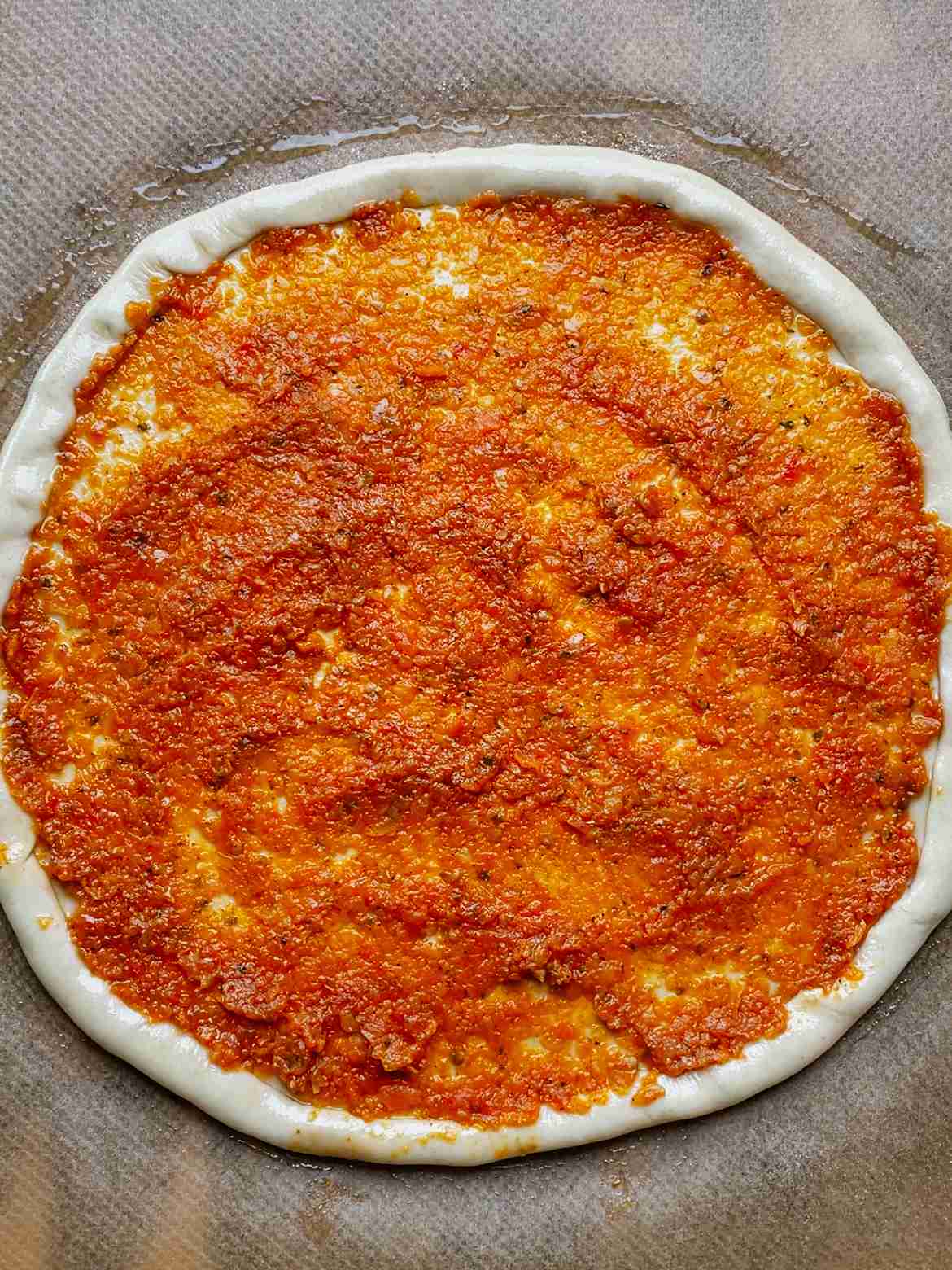 pizza dough with tomato sauce before baking