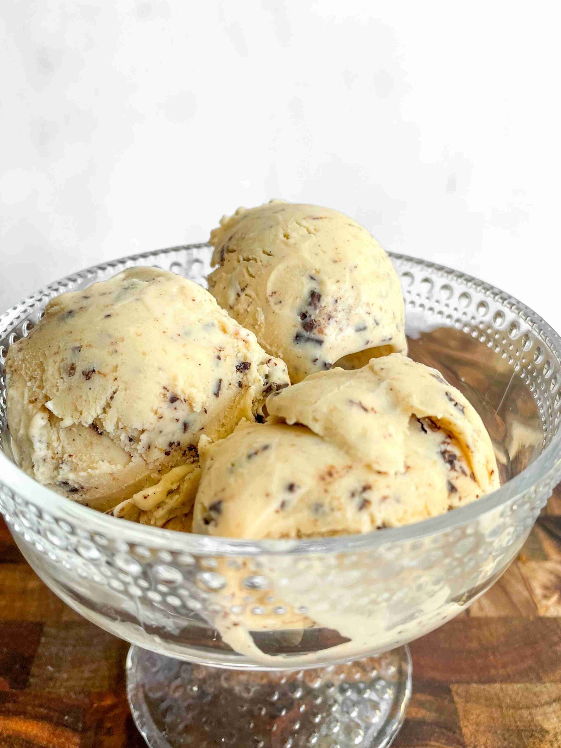 Close-up of hazelnut ice cream scoops studded with dark chocolate pieces, highlighting the rich, creamy texture.