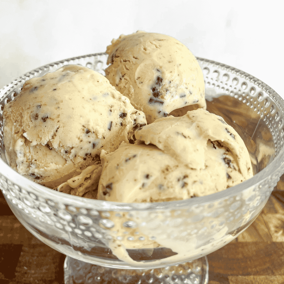 Close-up of hazelnut ice cream scoops studded with dark chocolate pieces, highlighting the rich, creamy texture.