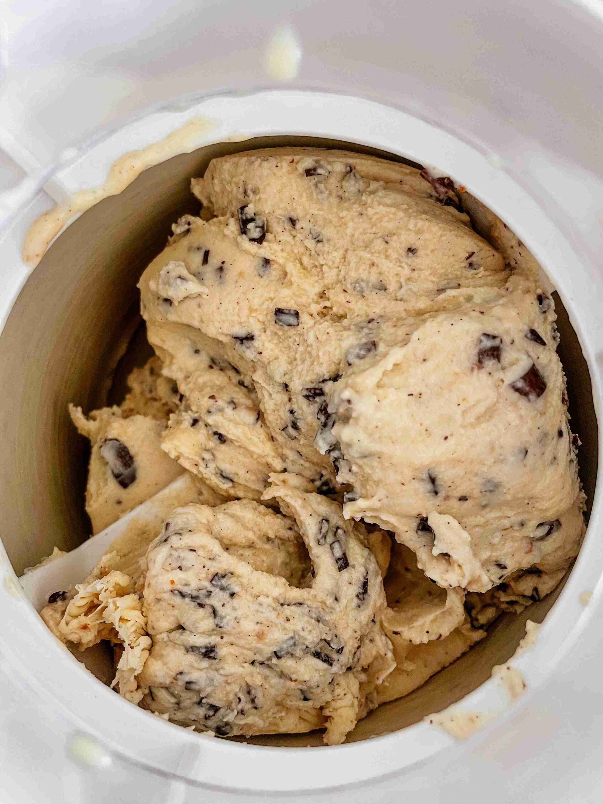 Hazelnut ice cream churning in an ice cream maker with dark chocolate shavings being added.