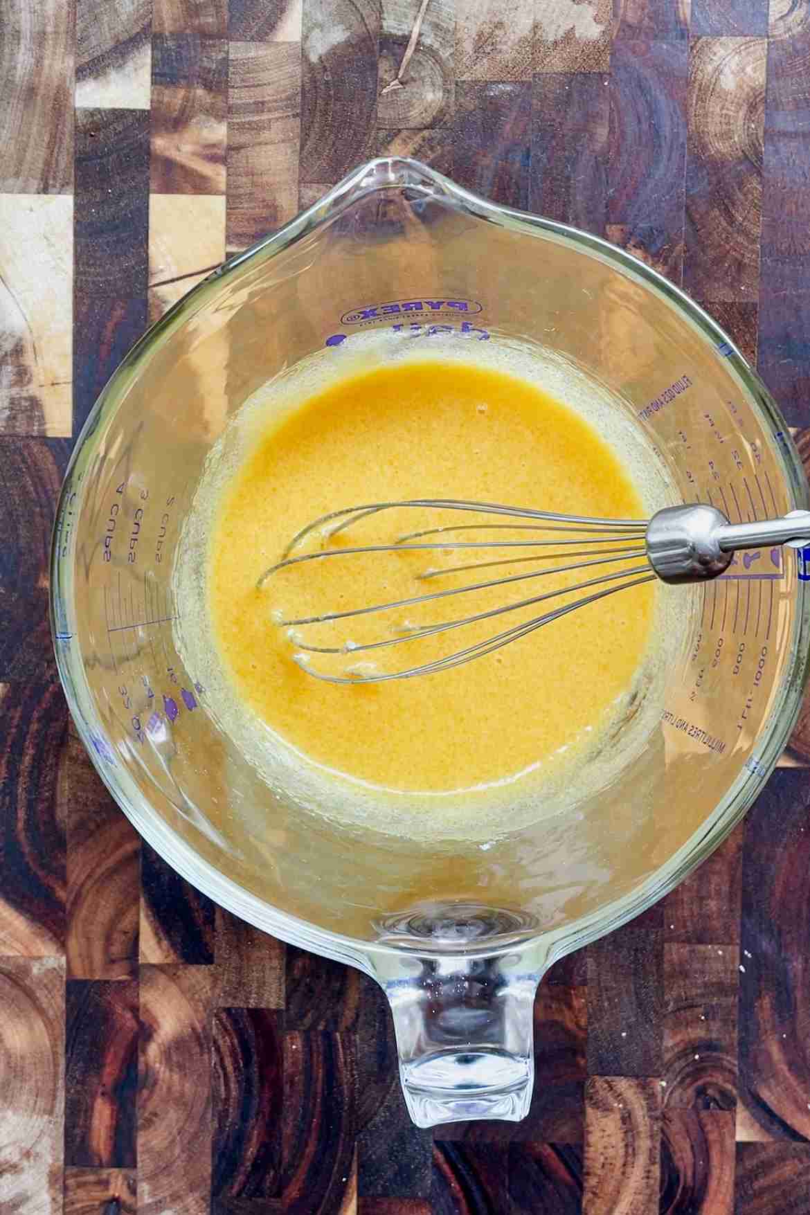 Whisked egg yolks and sugar in a mixing bowl, pale yellow and slightly thickened.