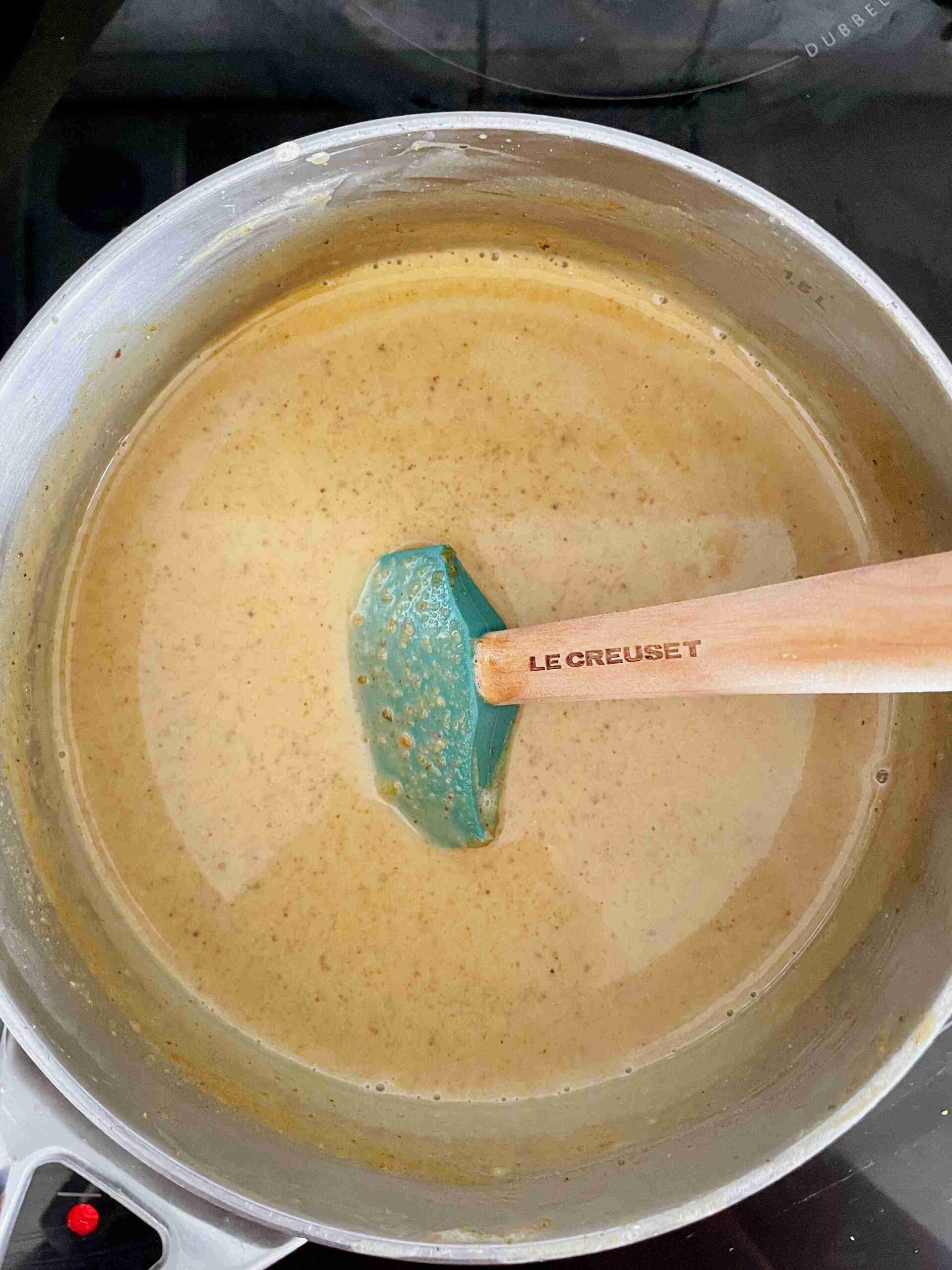 Pistachio ice cream custard cooking and thickening in a saucepan.