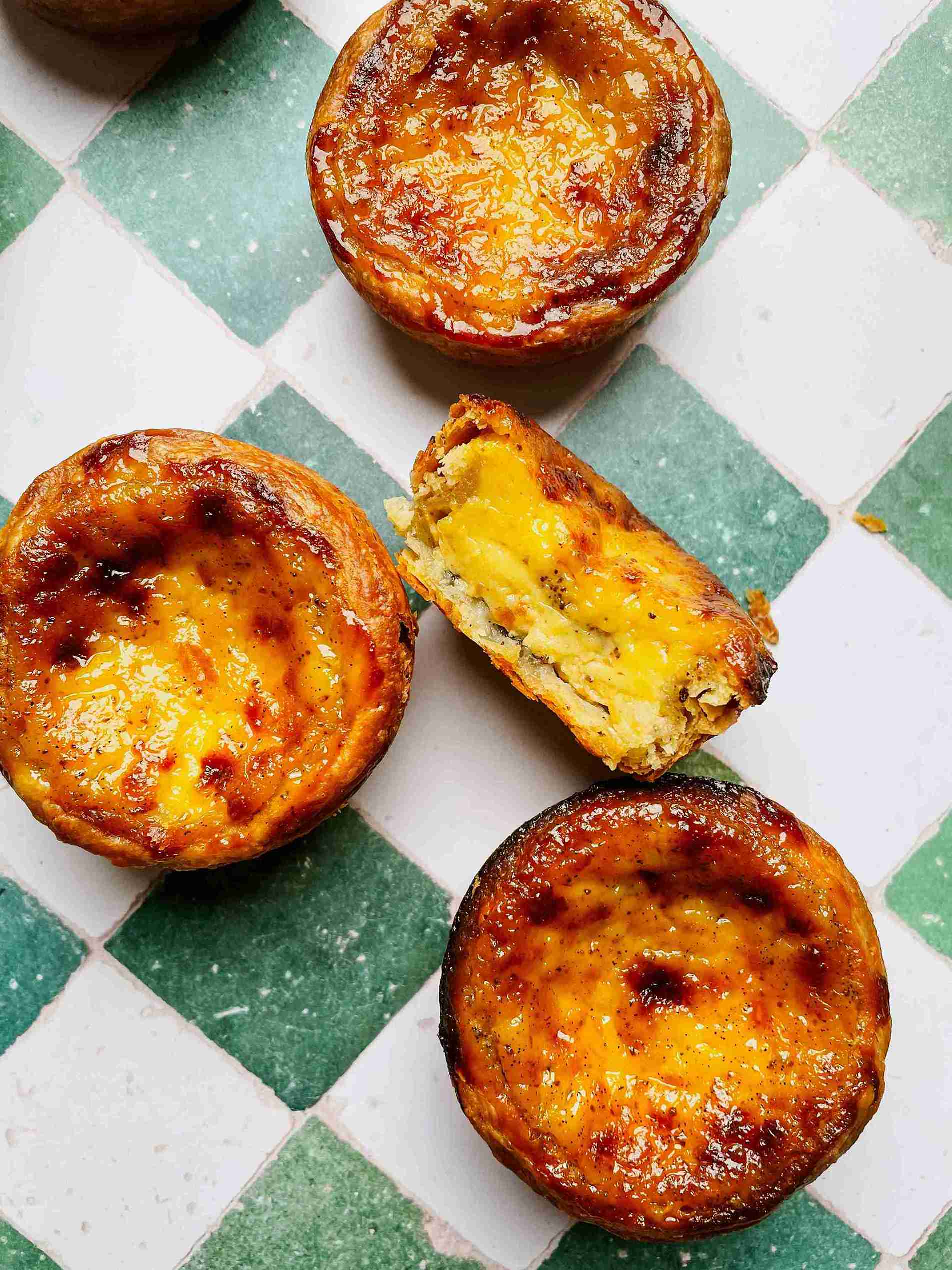 Close-up of a puff pastry egg tart cut in half showing the silky vanilla custard filling