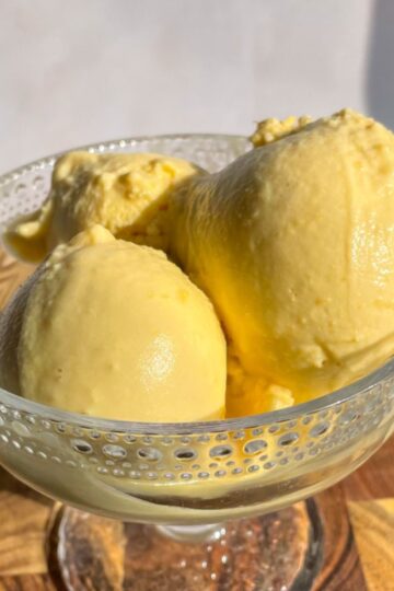 Scoops of coconut peach ice cream in a bowl made with fresh peaches.