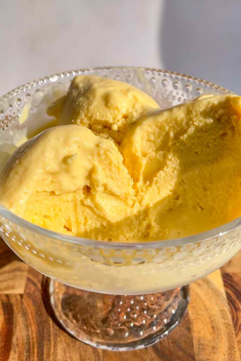 Scoops of coconut peach ice cream in a bowl made with fresh peaches.