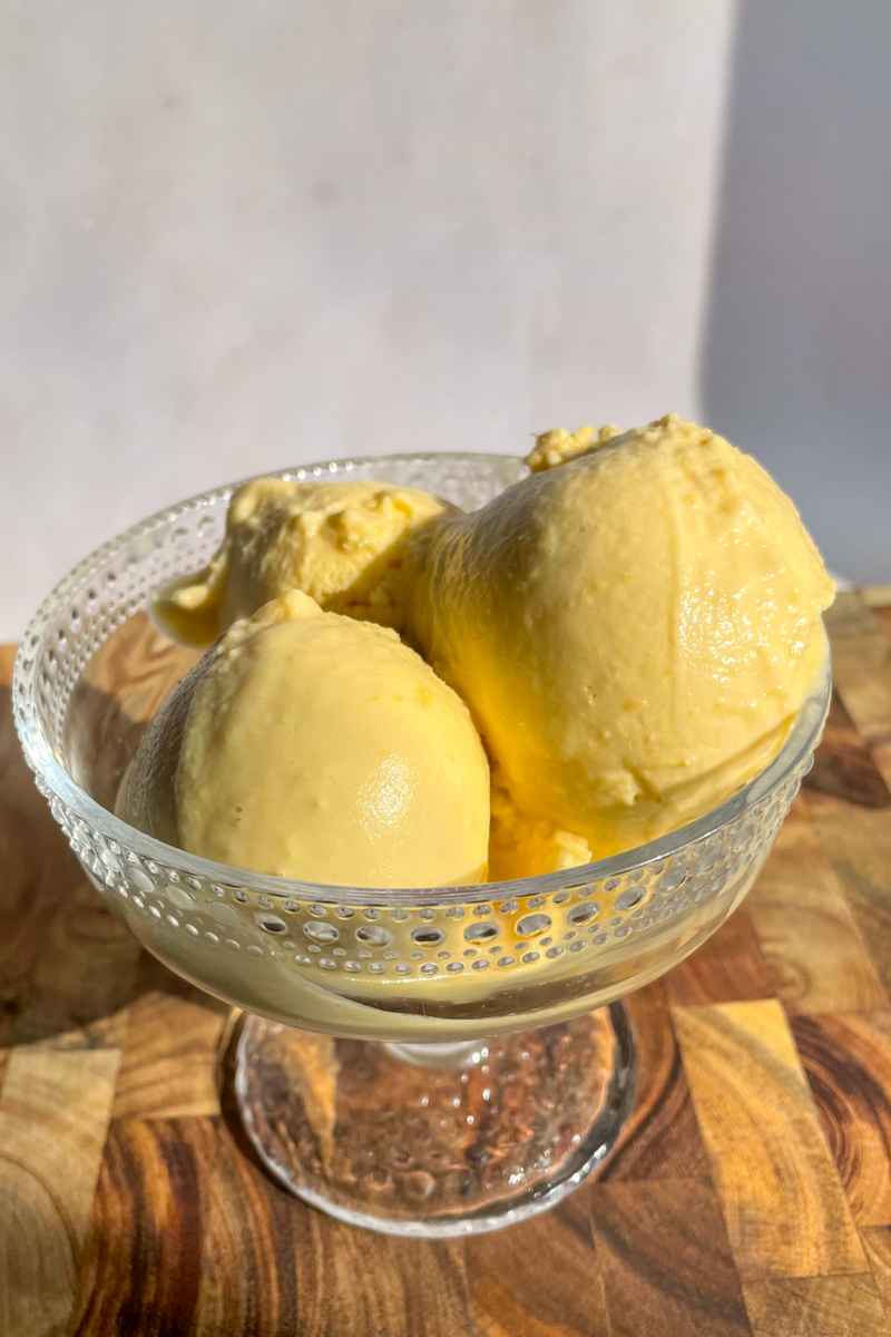 Scoops of coconut peach ice cream in a bowl made with fresh peaches.