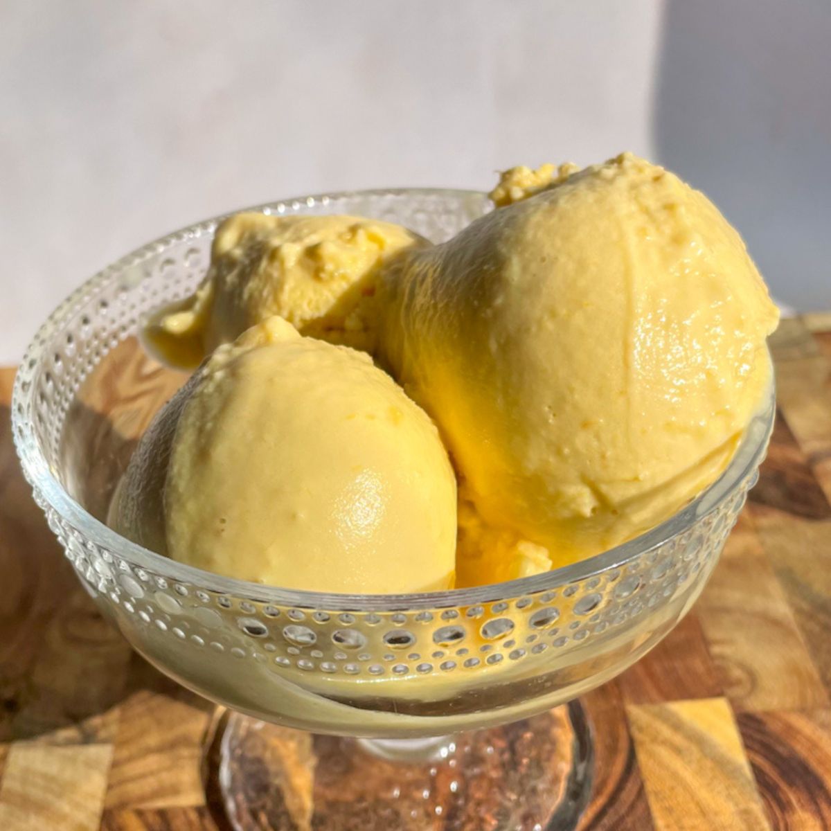 Scoops of coconut peach ice cream in a bowl made with fresh peaches.