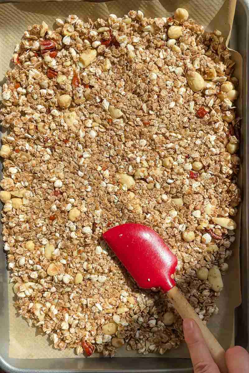 Sourdough granola pressed into a thin layer on a parchment lined baking sheet
