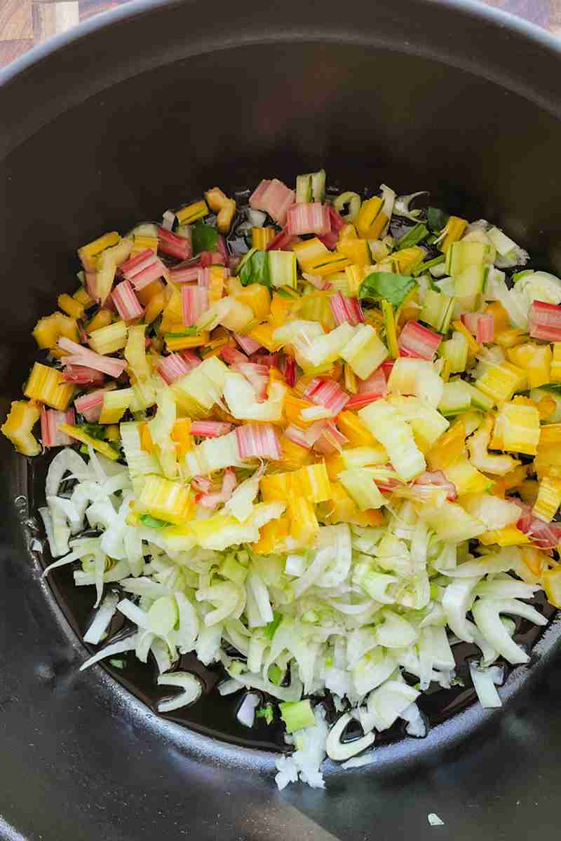 Sliced fennel and onion cooking in a pot for swiss chard soup.